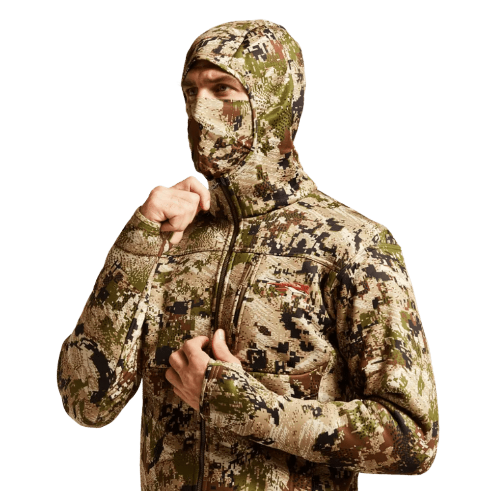 Mand iført Sitka Traverse hoodie i camouflage. Varm, strækbar fleecehoodie med indbygget halsedisse